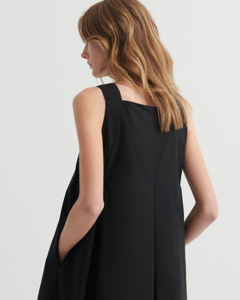 Woman wearing a black sleeveless dress against a white background