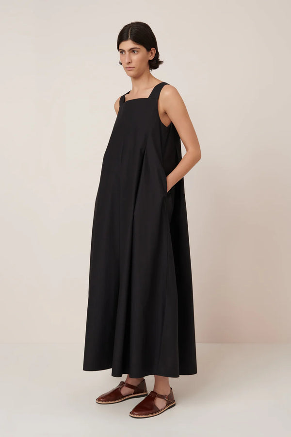 Woman wearing a black sleeveless dress against a plain background