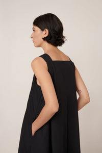 Woman wearing a black sleeveless dress against a plain background