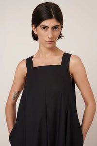 Woman wearing a black sleeveless dress against a plain background