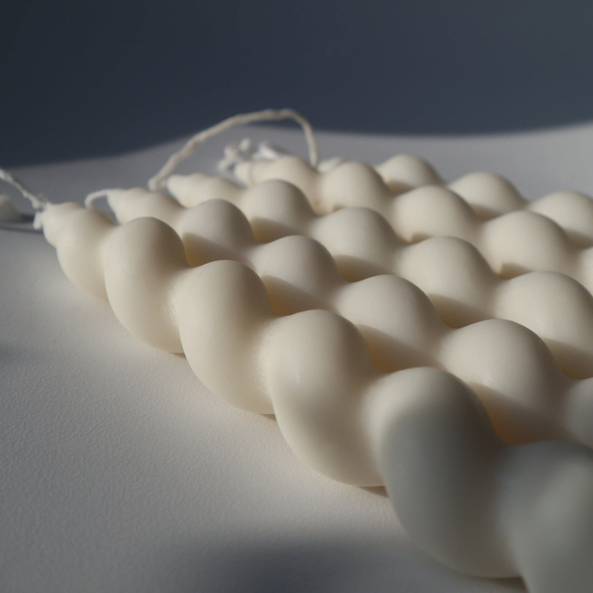 Set of white twisted taper candles on a textured surface with a dark background