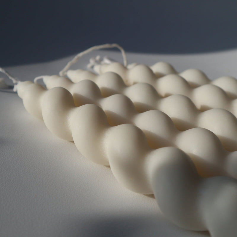 Set of white twisted taper candles on a textured surface with a dark background