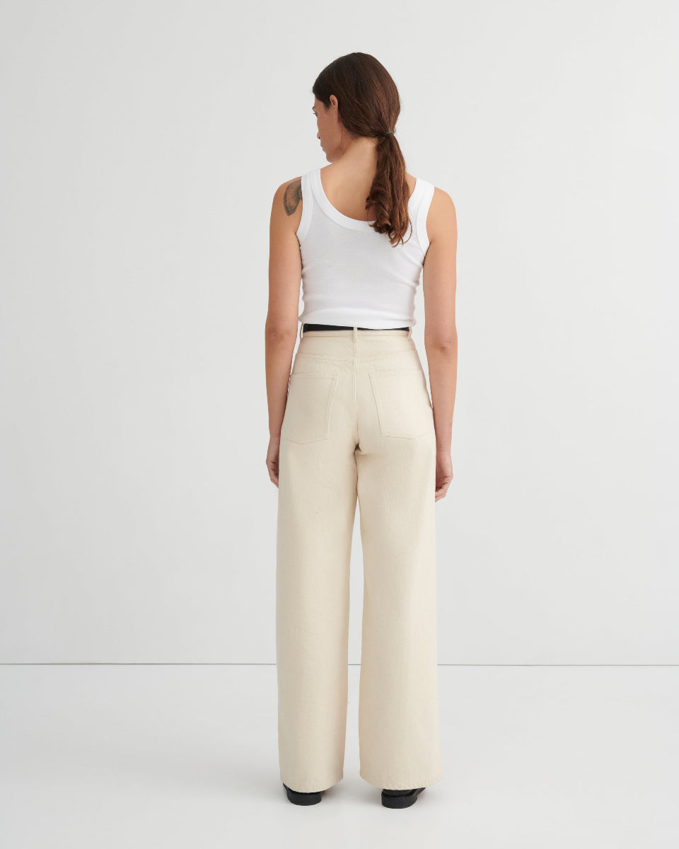 Woman wearing a white tank top and beige pants on a white background