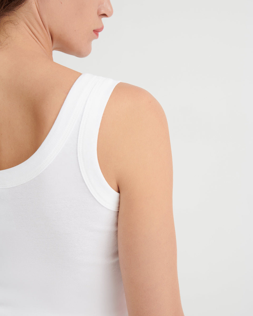 Person wearing a white tank top on a light gray background
