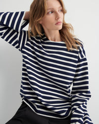 Woman wearing a navy and white striped top against a plain background
