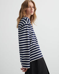 Woman wearing a navy and white striped shirt on a light gray background