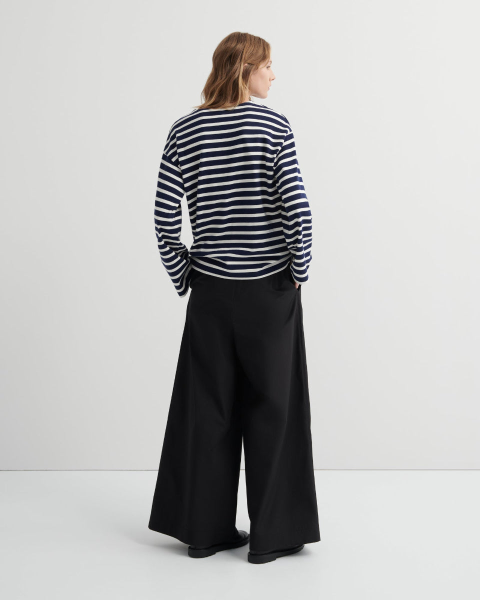 Person wearing a striped top and black wide-leg pants against a white background