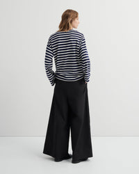Person wearing a striped top and black wide-leg pants against a white background