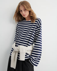 Woman wearing a navy and white striped top with a plain background