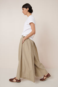 Person wearing a white t-shirt and beige striped pants on a plain background