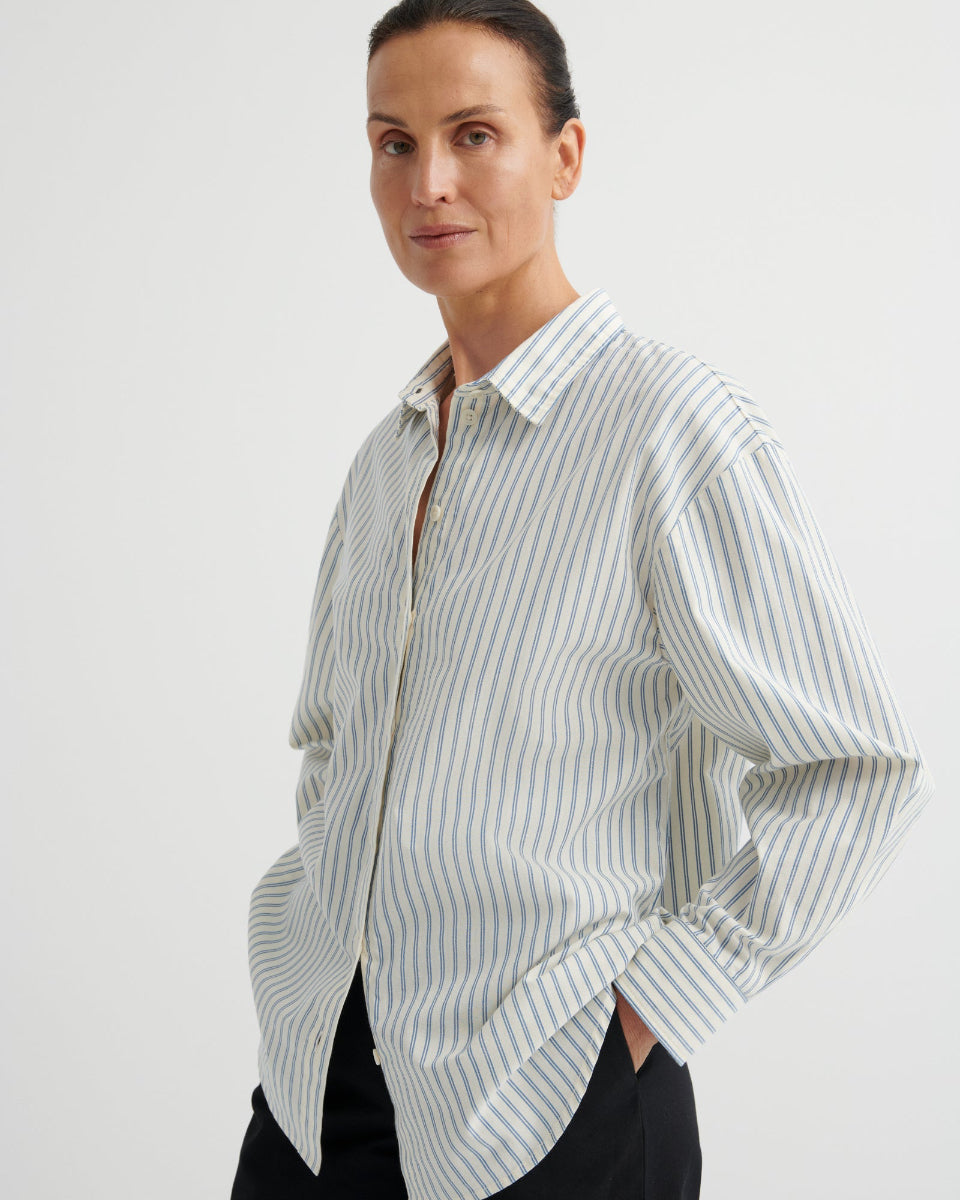 Woman wearing a white and blue striped shirt on a plain background