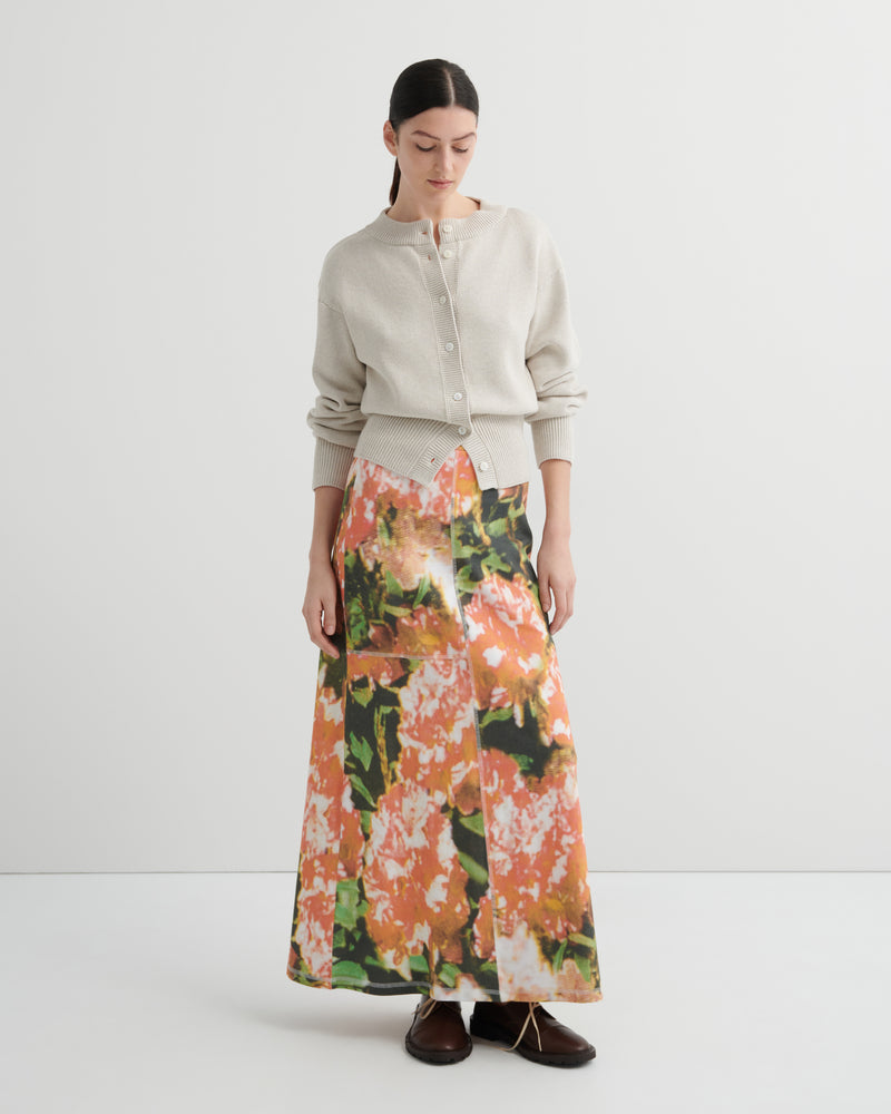 Woman wearing a floral skirt and light-colored cardigan on a white background