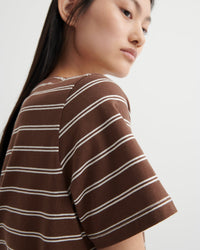Woman wearing a brown and white striped shirt against a plain background