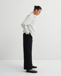 Person wearing a striped shirt and black pants on a white background