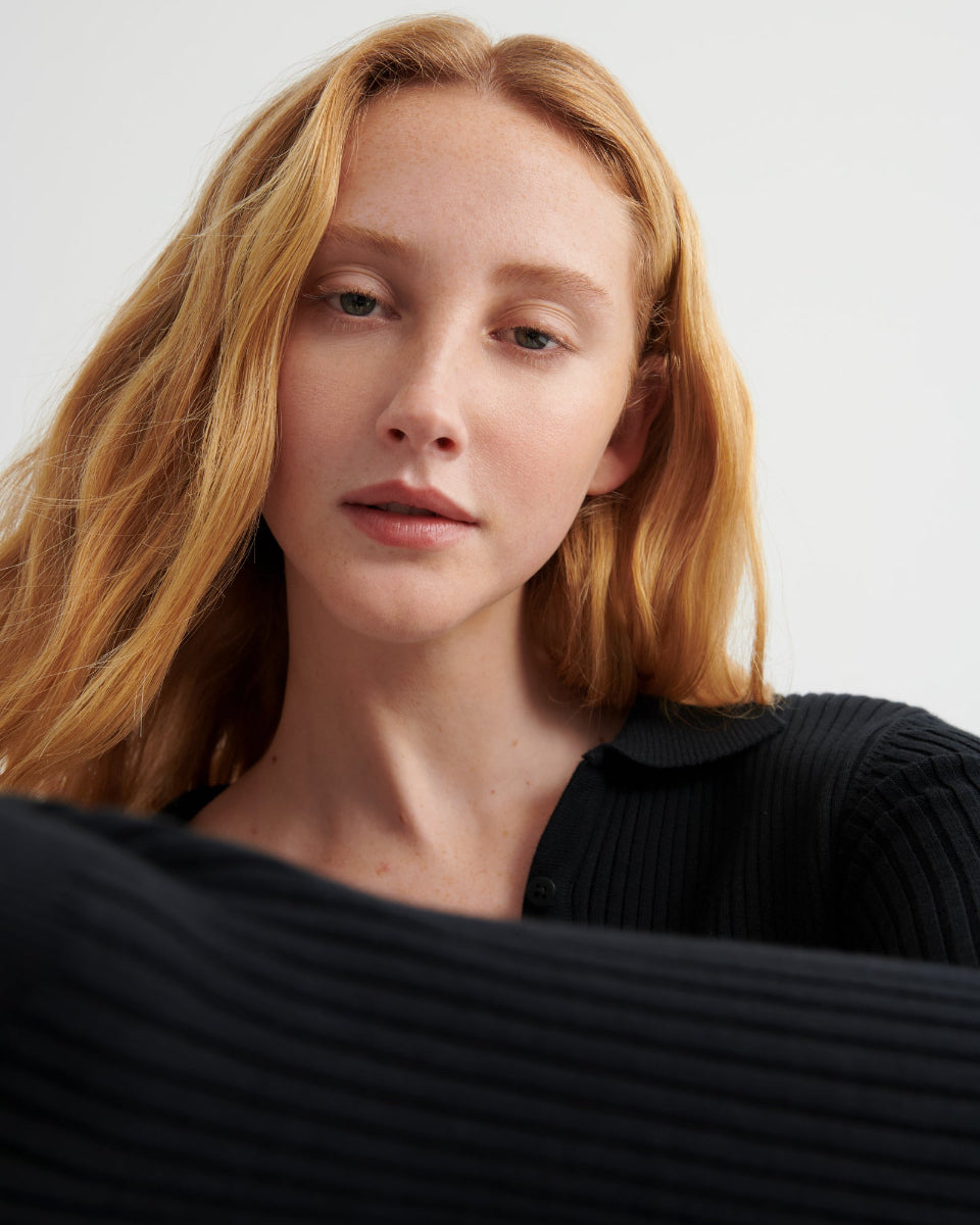 Woman with blonde hair wearing a black top against a white background