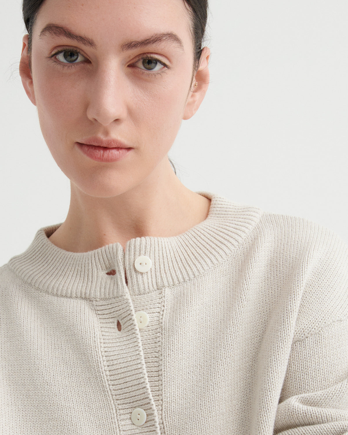 Person wearing a light beige cardigan on a plain background
