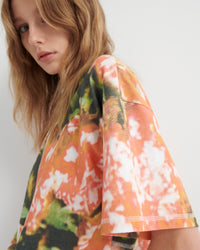 Person wearing a colorful floral patterned top against a plain background