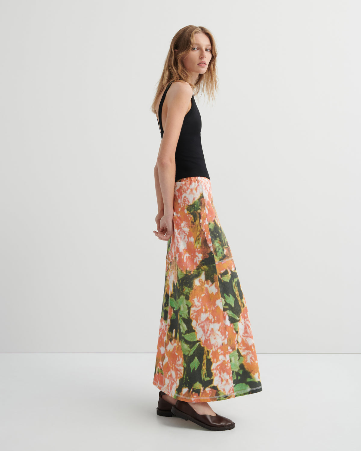 Woman wearing a black top and floral skirt on a white background