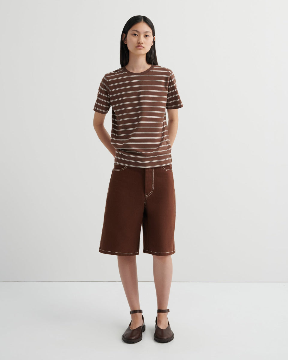 Person wearing a brown and white striped shirt and brown shorts on a white background