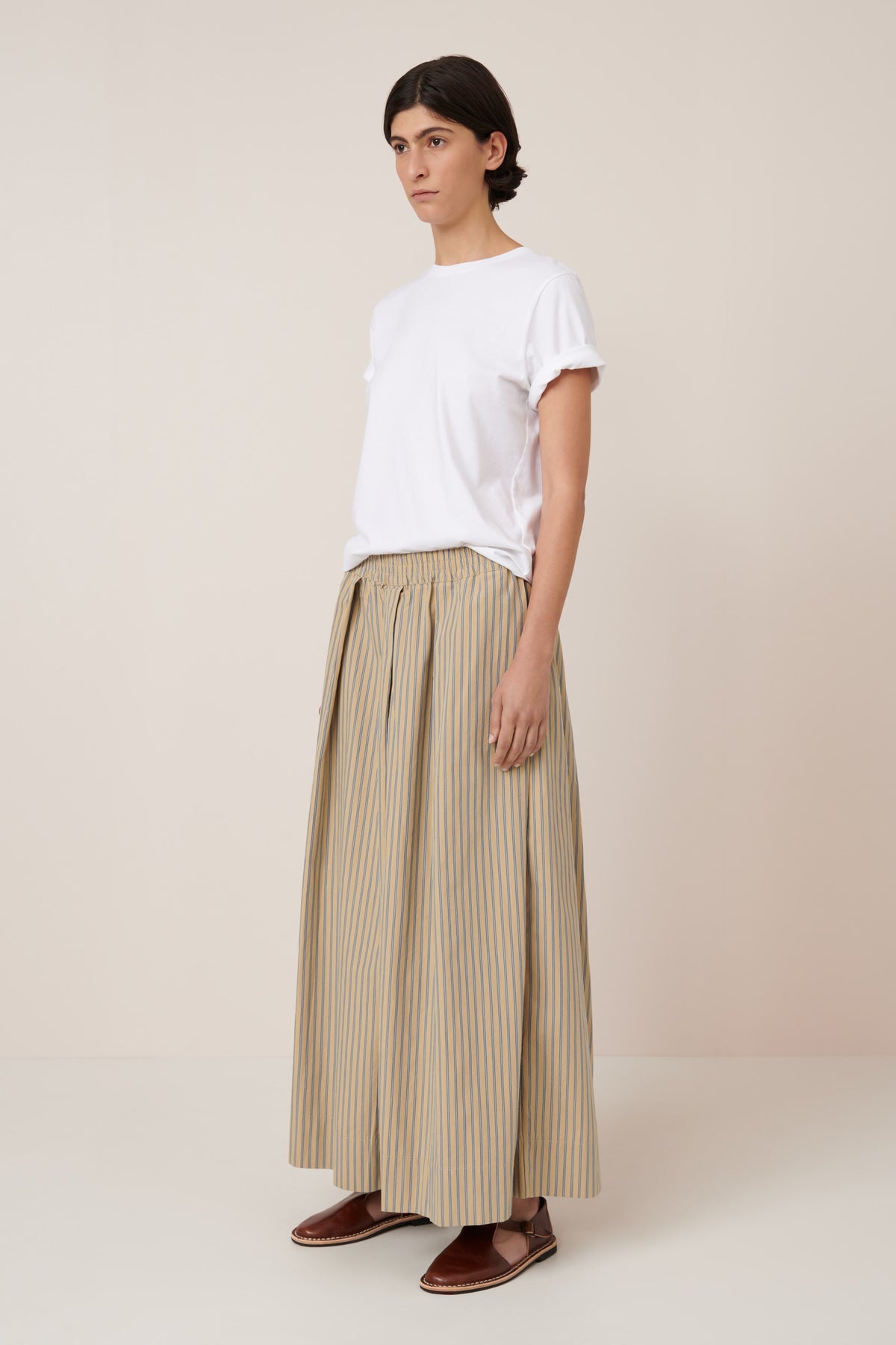 Person wearing a white t-shirt and beige striped pants on a plain background