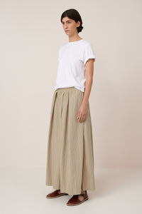 Person wearing a white t-shirt and beige striped pants on a plain background