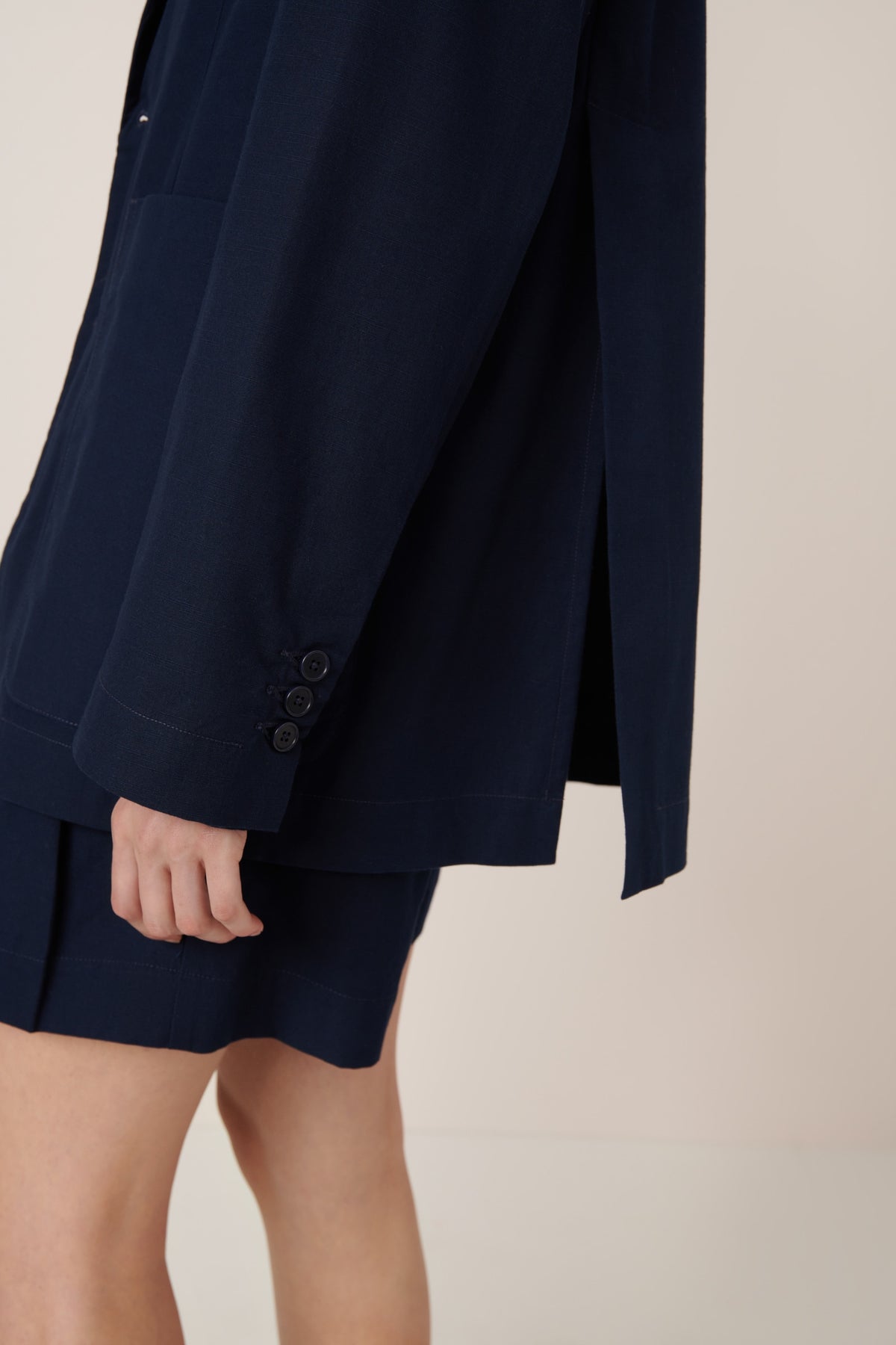 Navy blue blazer and shorts worn by a person on a beige background