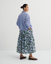 Woman wearing a blue sweater and floral skirt on a white background