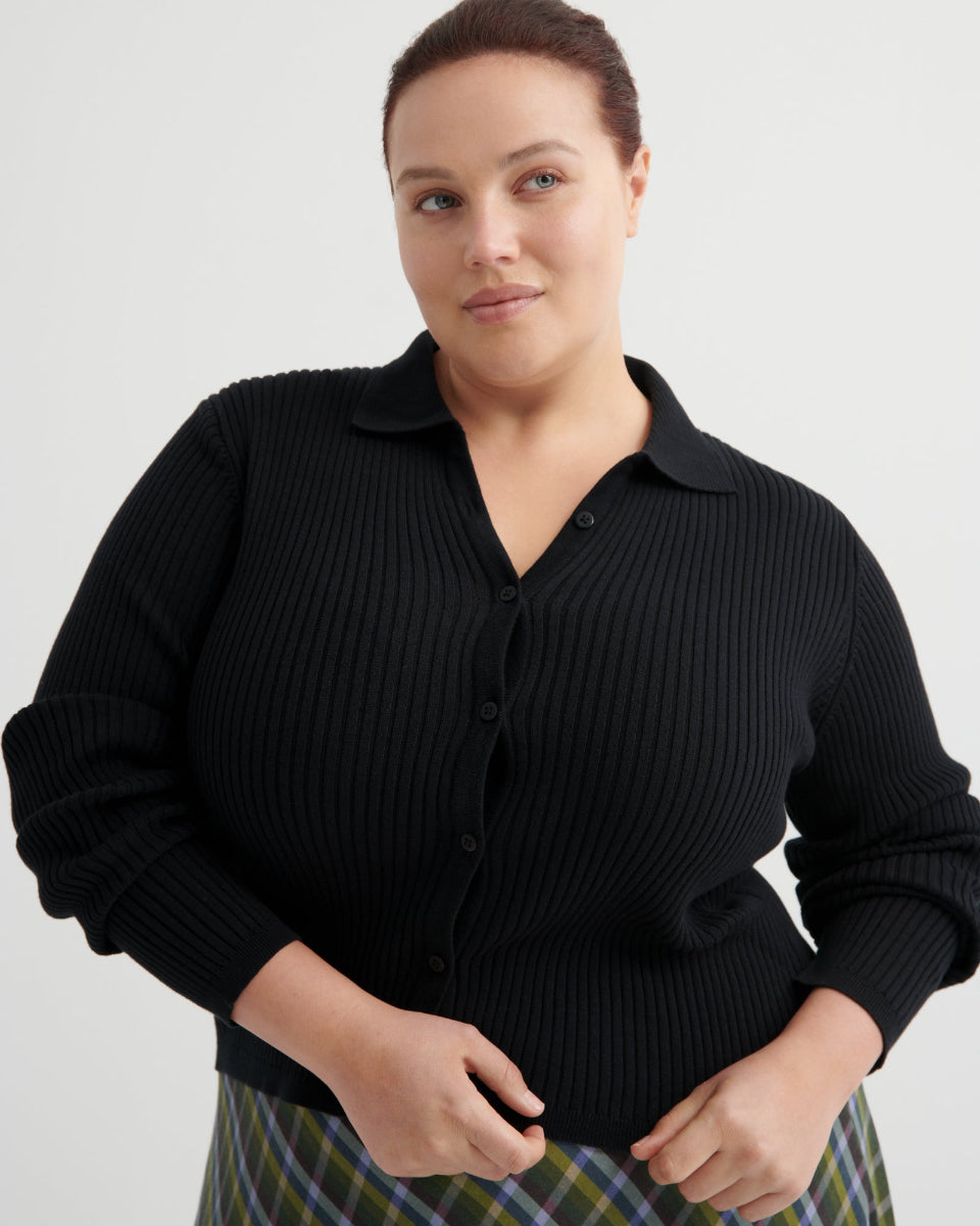 Woman wearing a black ribbed sweater on a light gray background