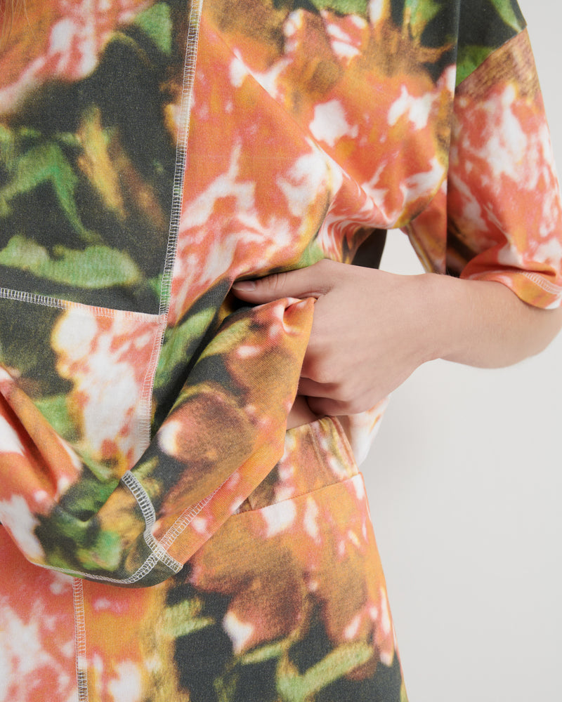 Close-up of a colorful floral patterned fabric with a hand holding it.
