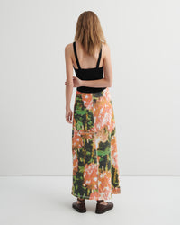 Woman wearing a black top and colorful floral skirt on a white background