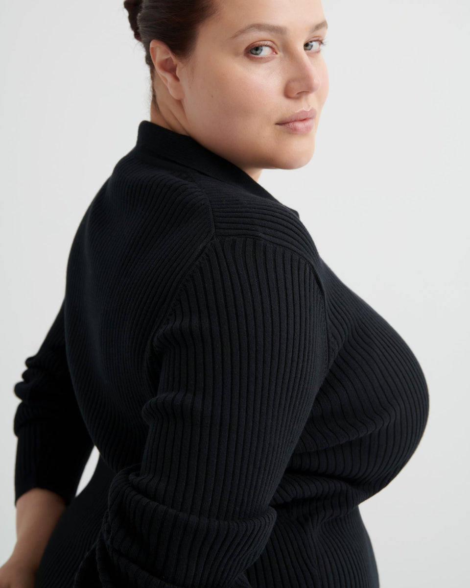 Woman wearing a black ribbed sweater against a light gray background