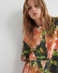 Person wearing a colorful floral-patterned shirt against a plain background