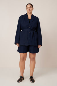 Woman wearing a navy blue suit with shorts on a plain background