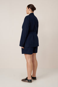 Person wearing a navy blue suit on a plain background