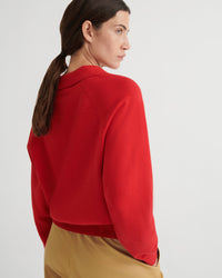 Backside of a person looking past their shoulder wearing a red knit sweater on a white background