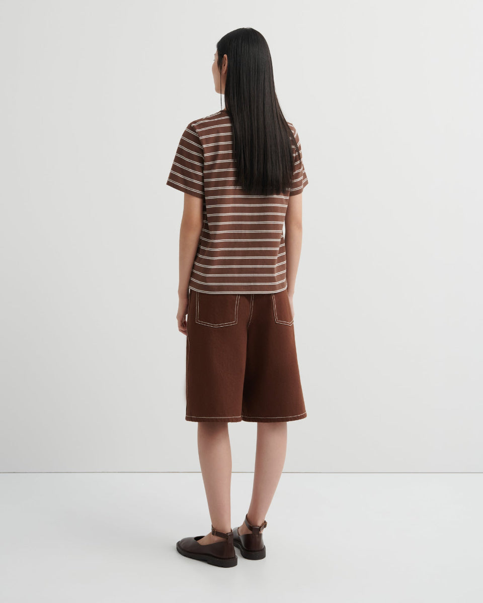 Person wearing a striped shirt and brown shorts on a white background