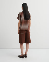 Person wearing a striped shirt and brown shorts on a white background
