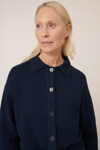 Woman wearing a navy blue cardigan against a plain background