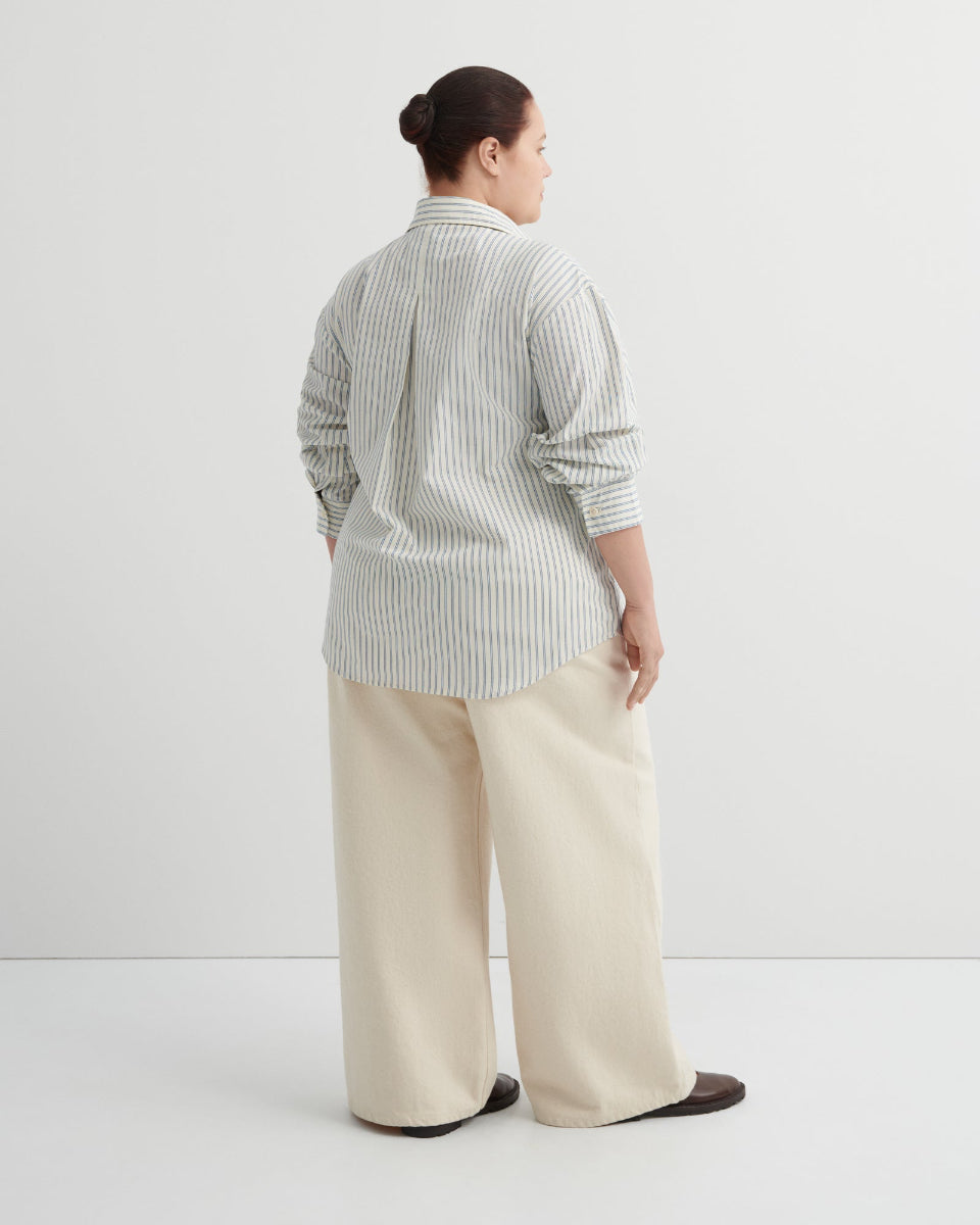 Person wearing a striped shirt and beige pants on a white background