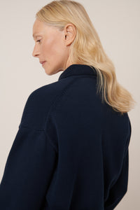 Person wearing a navy blue sweater against a beige background