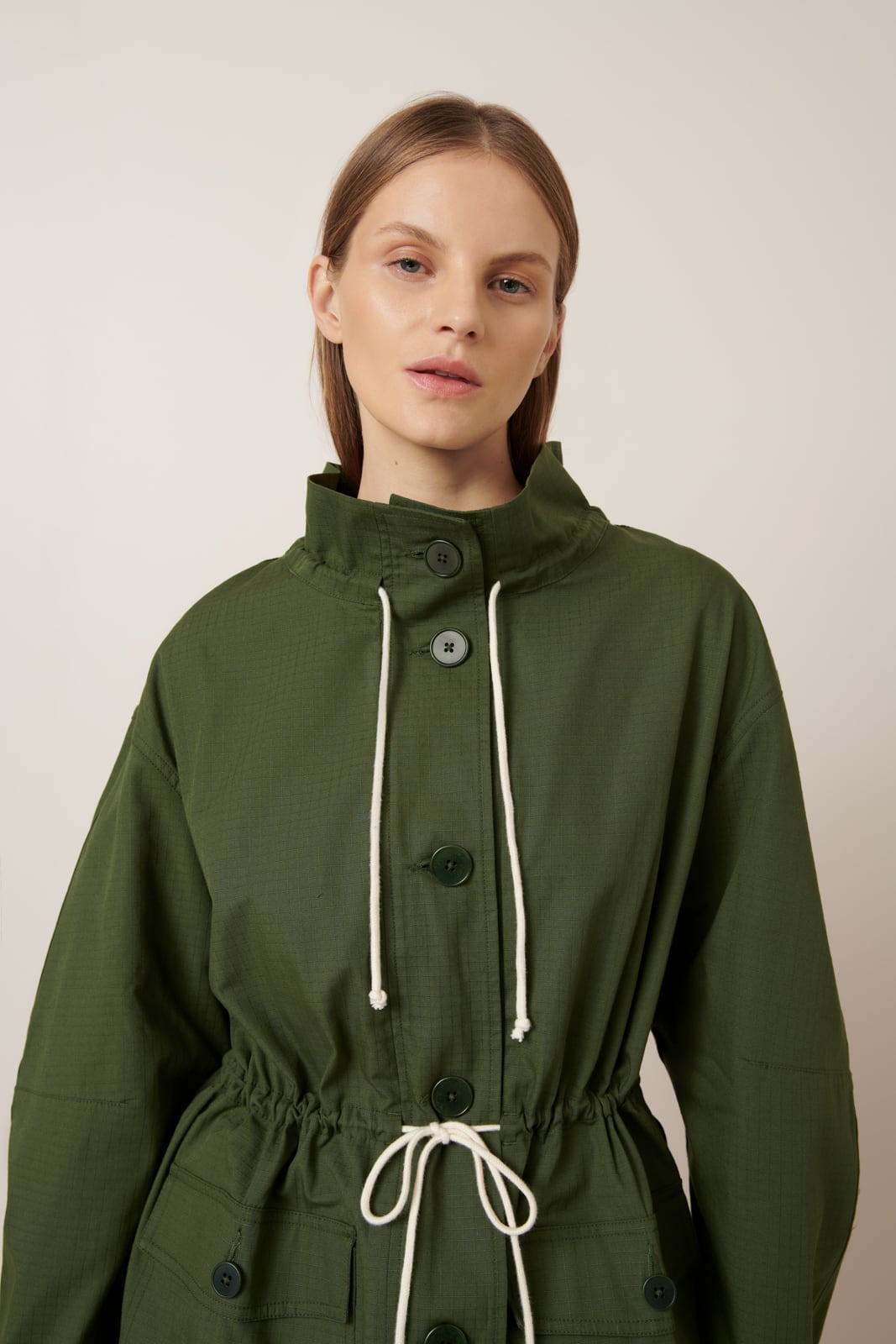 Woman wearing a green jacket with a neutral background