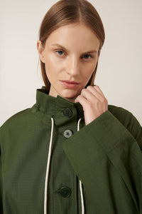Woman wearing a green coat with a neutral background