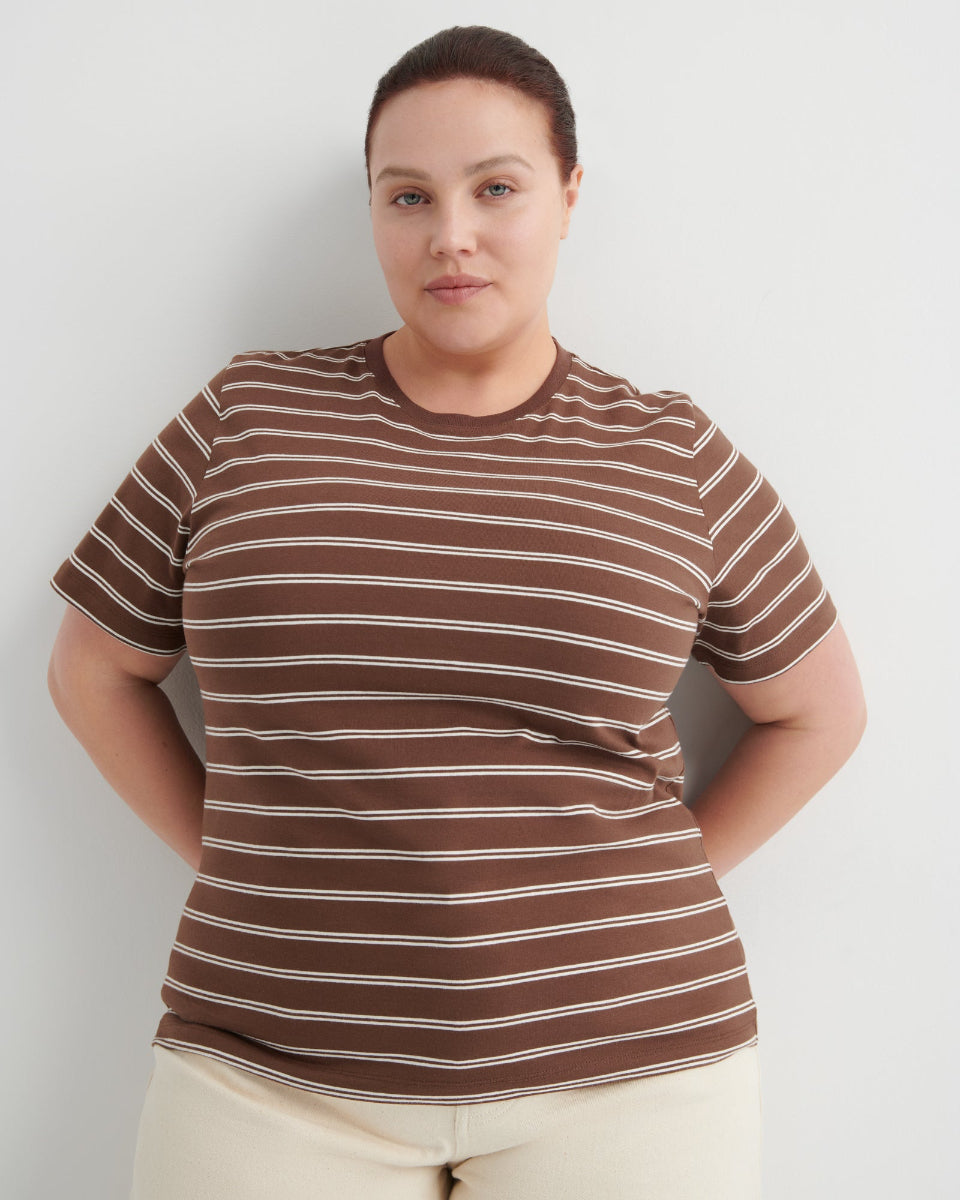 Person wearing a brown and white striped shirt against a plain background