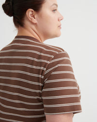 Person wearing a brown and white striped shirt on a plain background