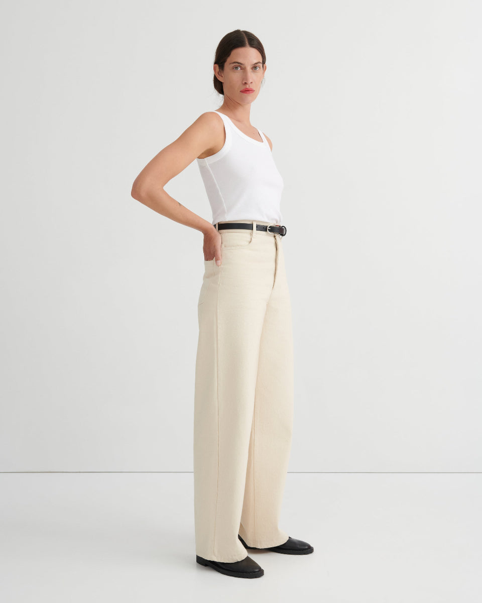 Woman wearing a white sleeveless top and beige wide-leg pants on a white background