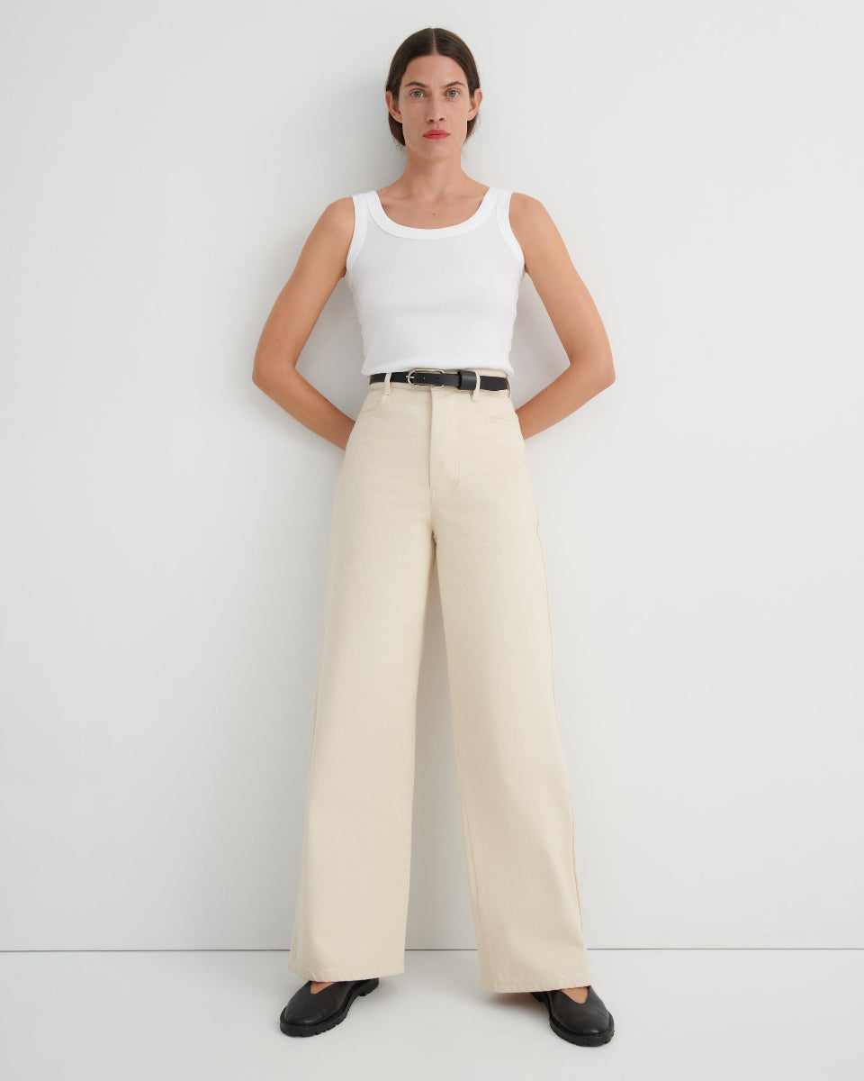 Woman wearing a white sleeveless top and beige wide-leg pants against a white background