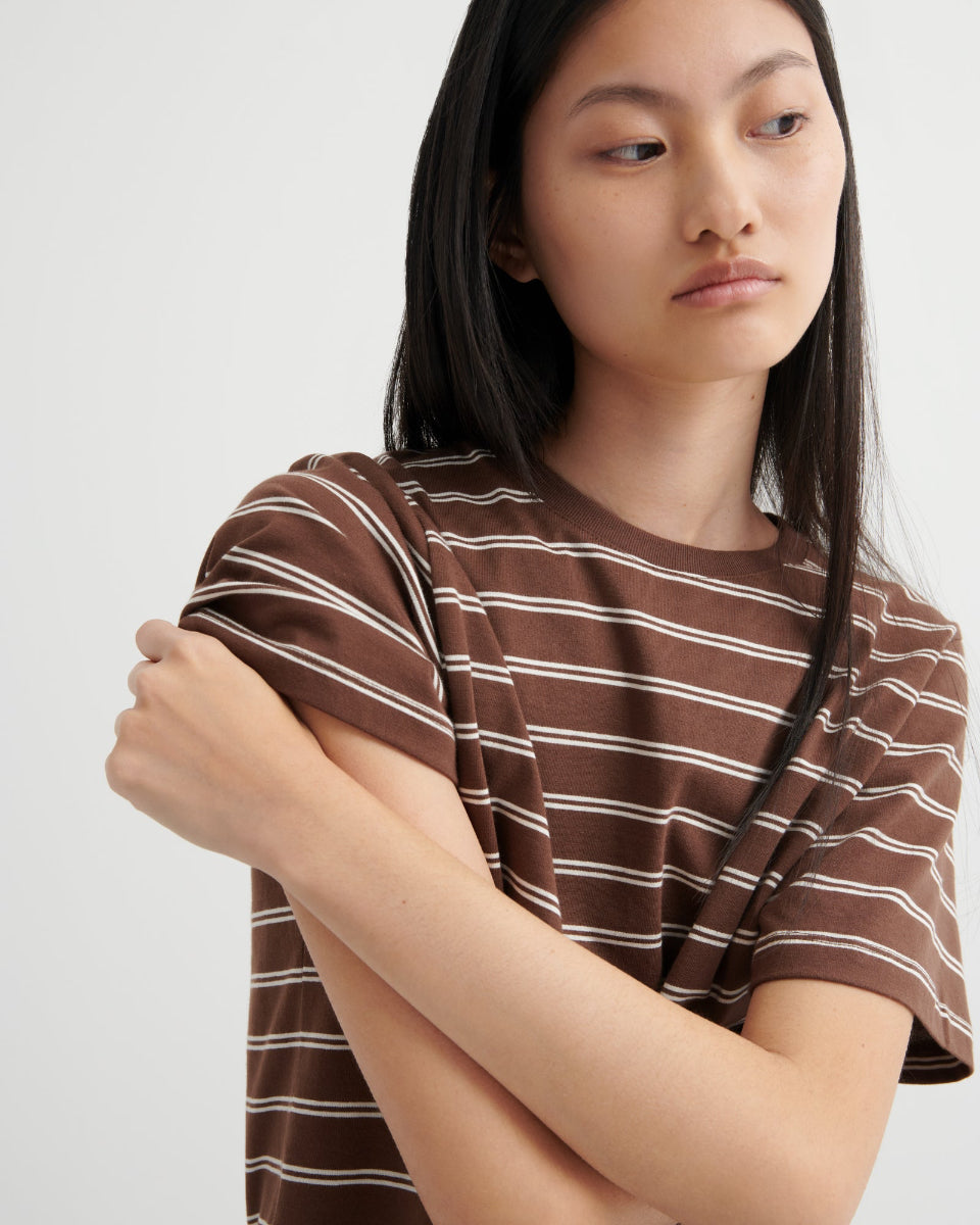 Person wearing a brown and white striped shirt against a plain background