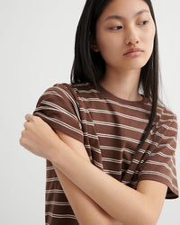 Person wearing a brown and white striped shirt against a plain background